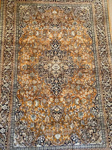 Tapis d'Orient en soie fine décor floral luxuriant sur fond orangé et médaillon